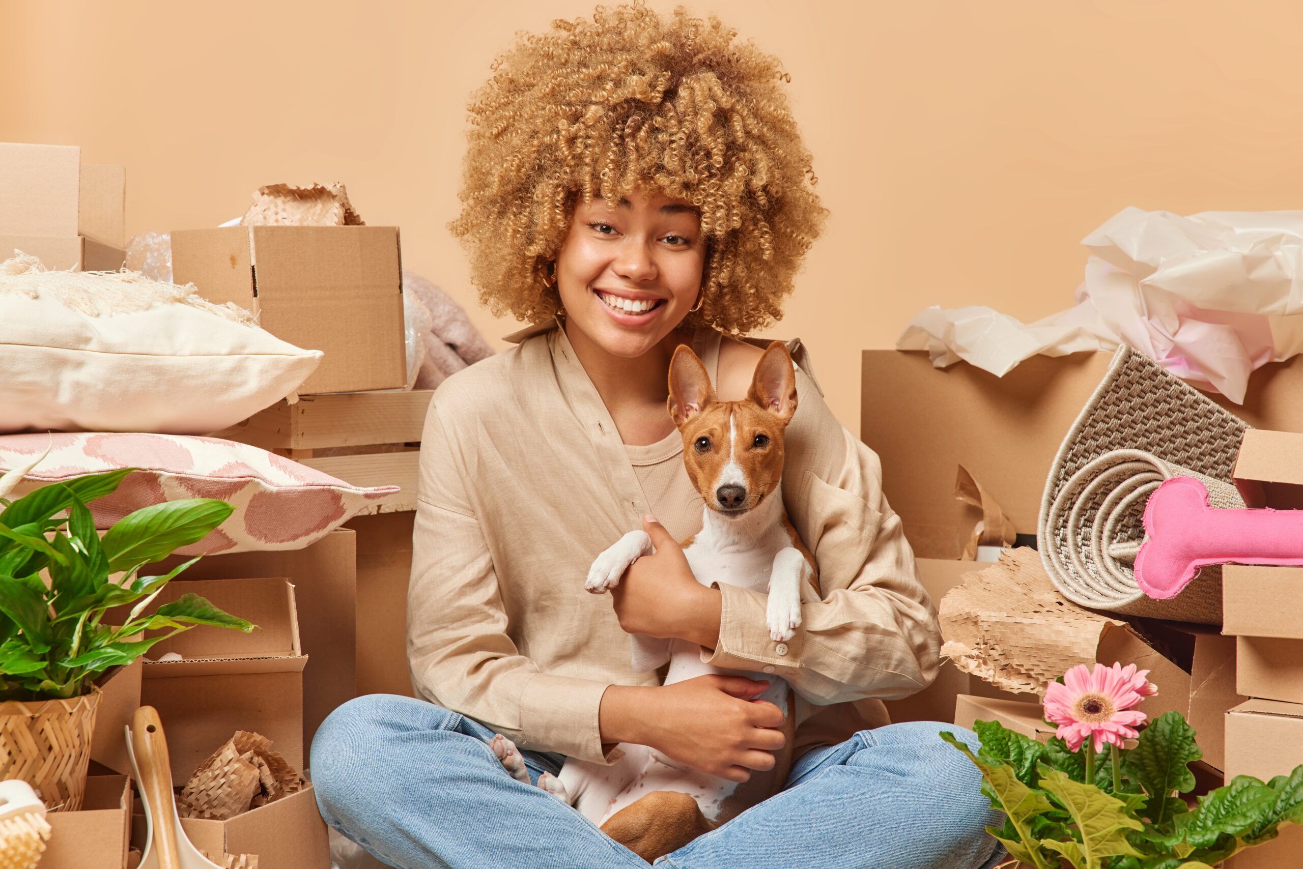 Woman sitting among moving boxes holding a small dog