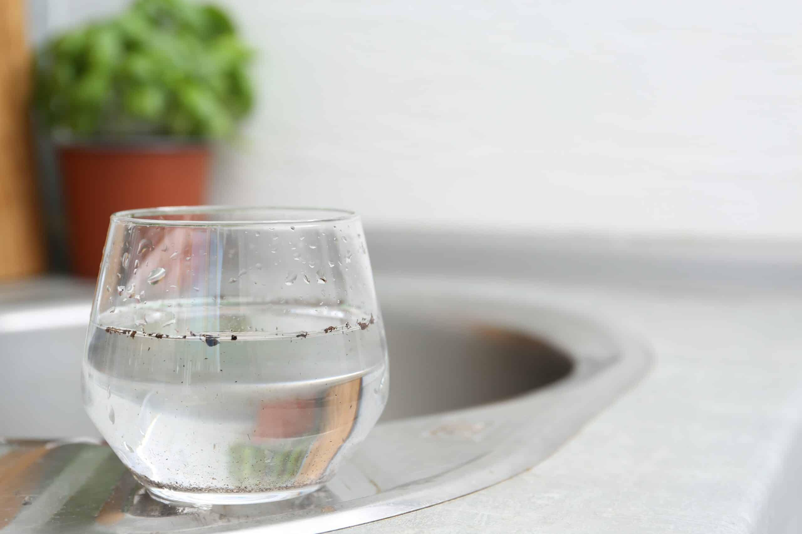 Glass of water on a kitchen worktop beside a stainless steel sink