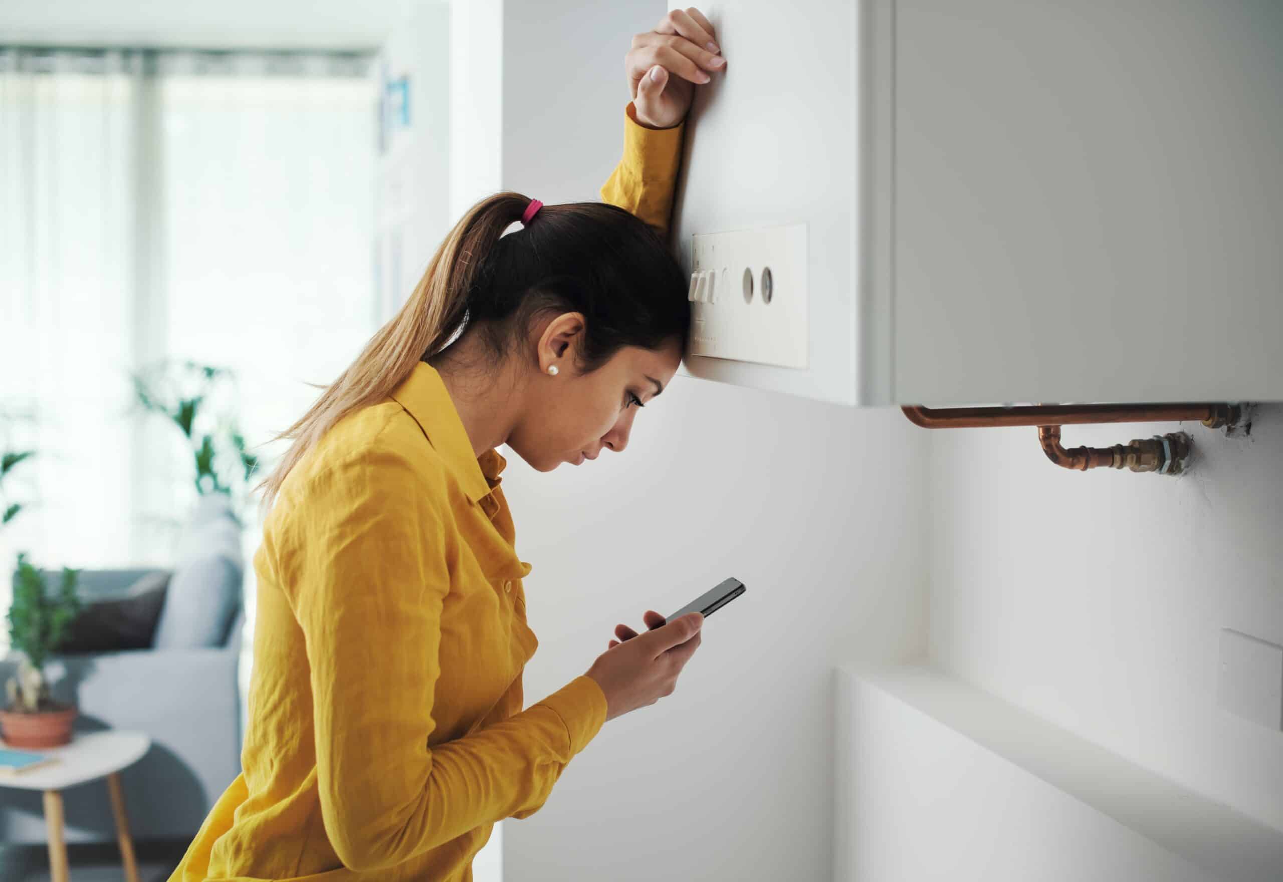 Woman looking at her phone beside exposed pipework on a wall