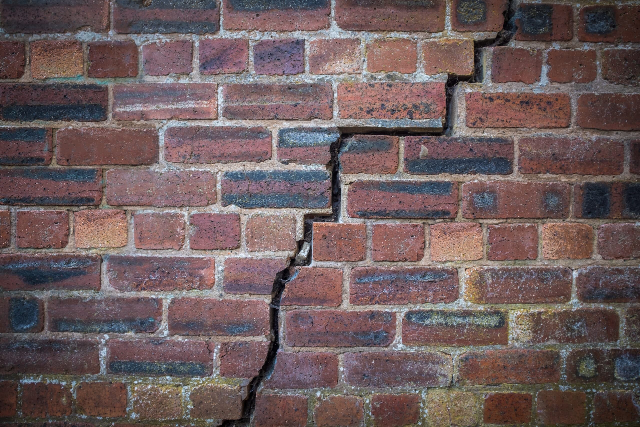 Large crack running down a brick wall
