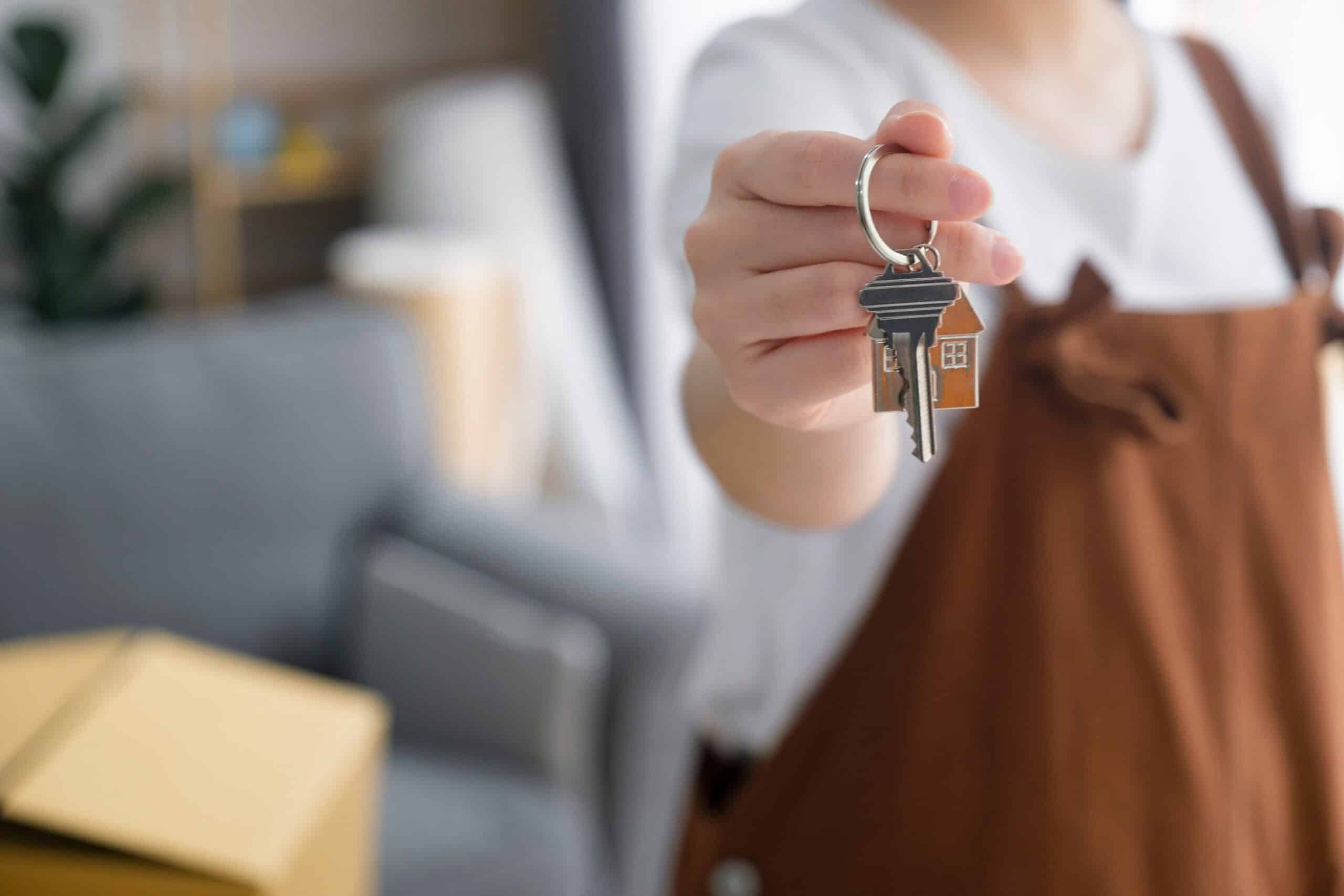 Hand holding out a set of keys in a furnished room