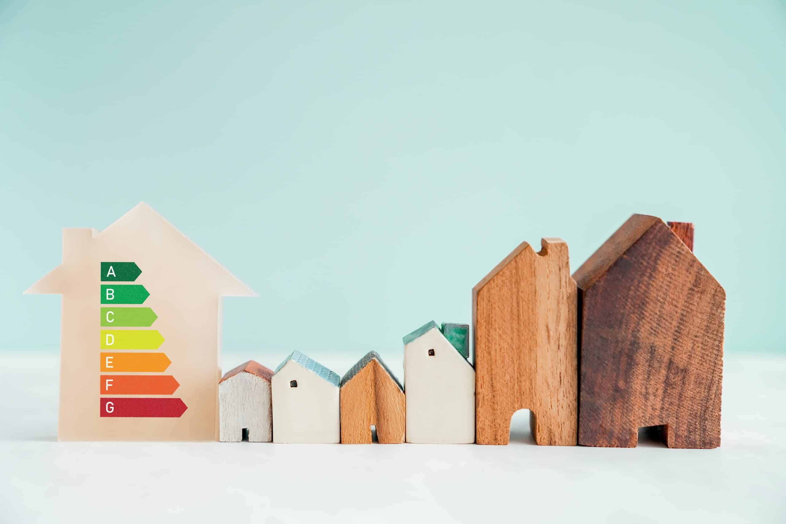 Wooden model houses beside a coloured energy efficiency rating chart