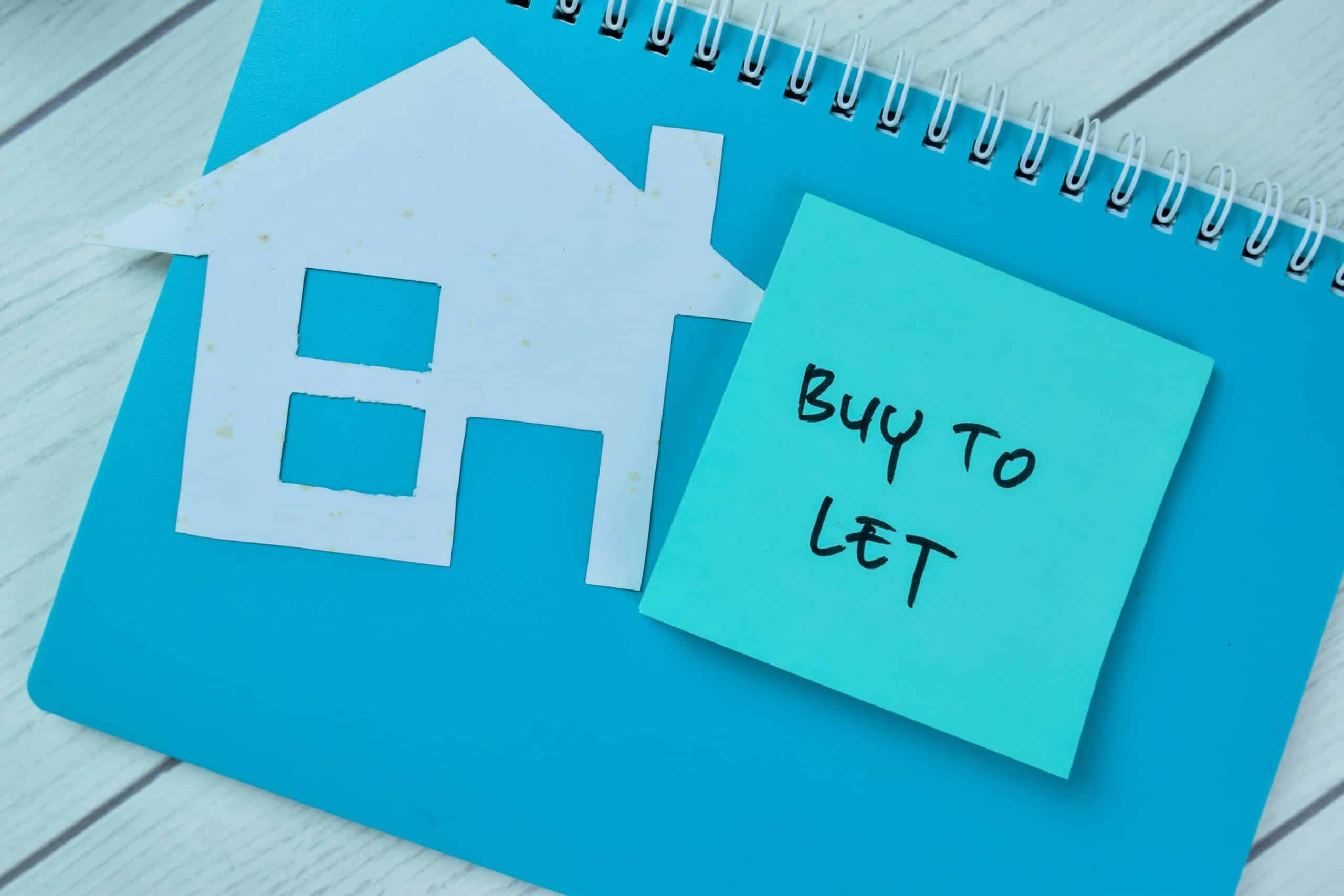 Paper house cut out beside a sticky note reading buy to let