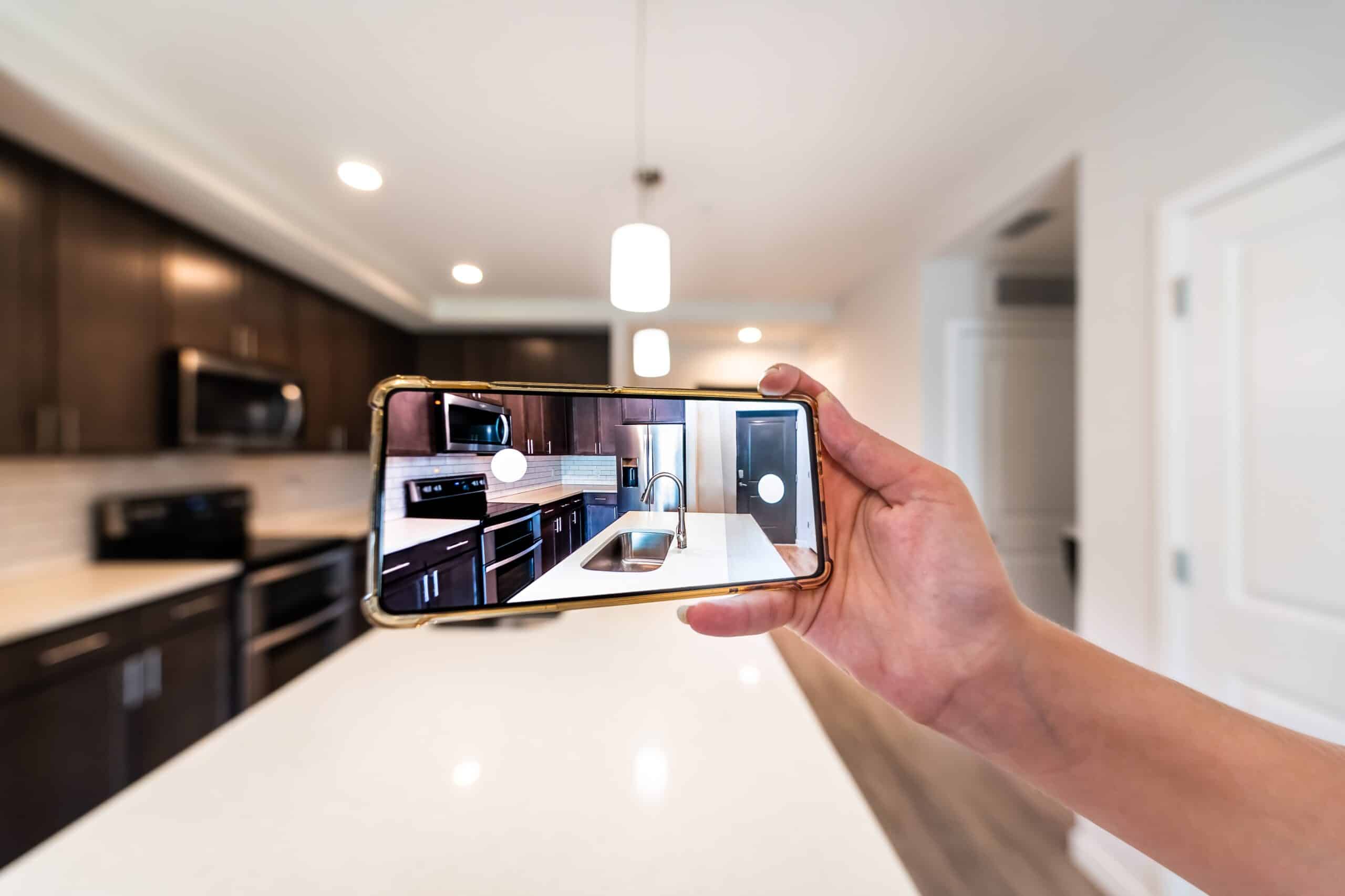 Hand photographing a modern kitchen on a smartphone
