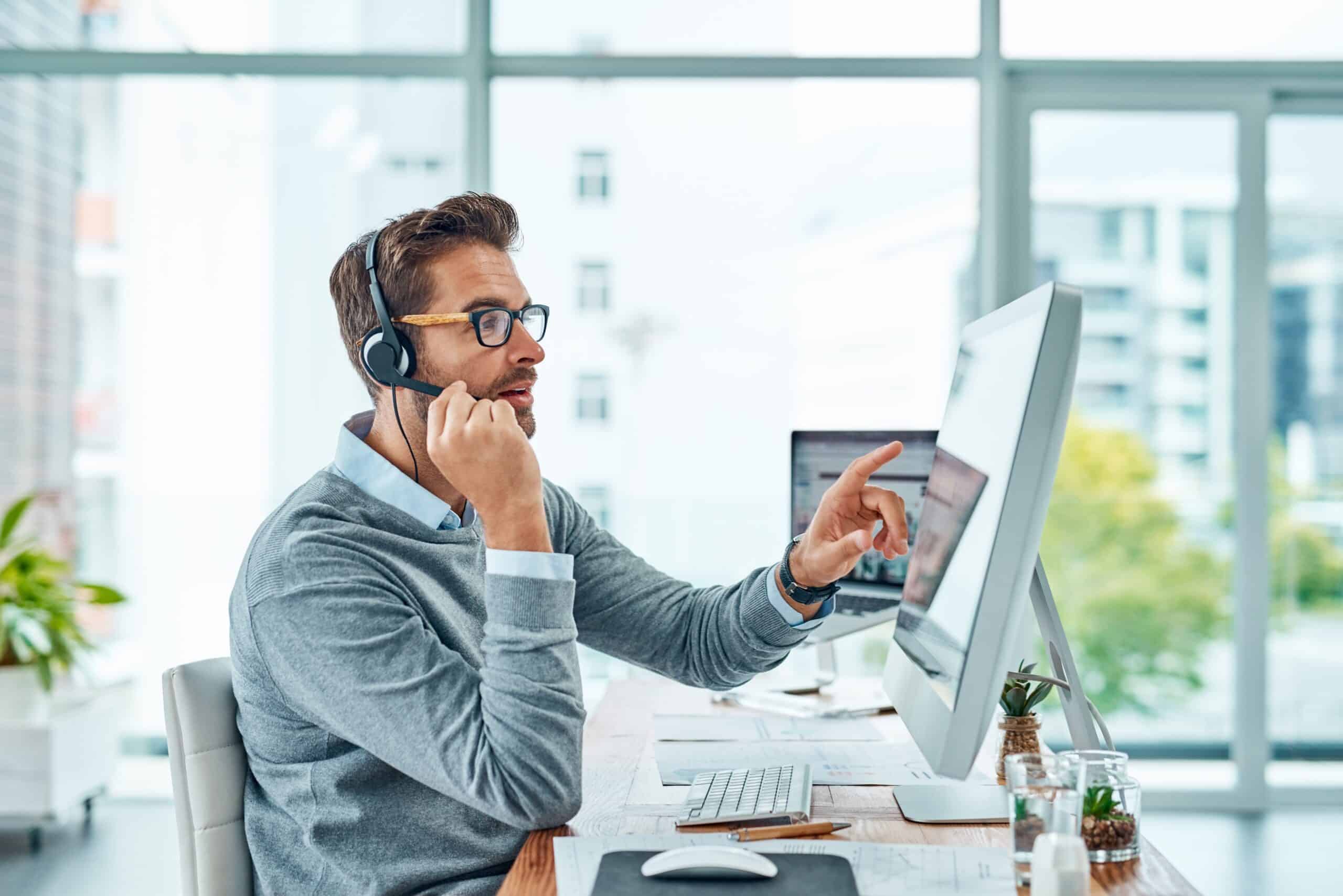 Man wearing a headset working at a computer in an office