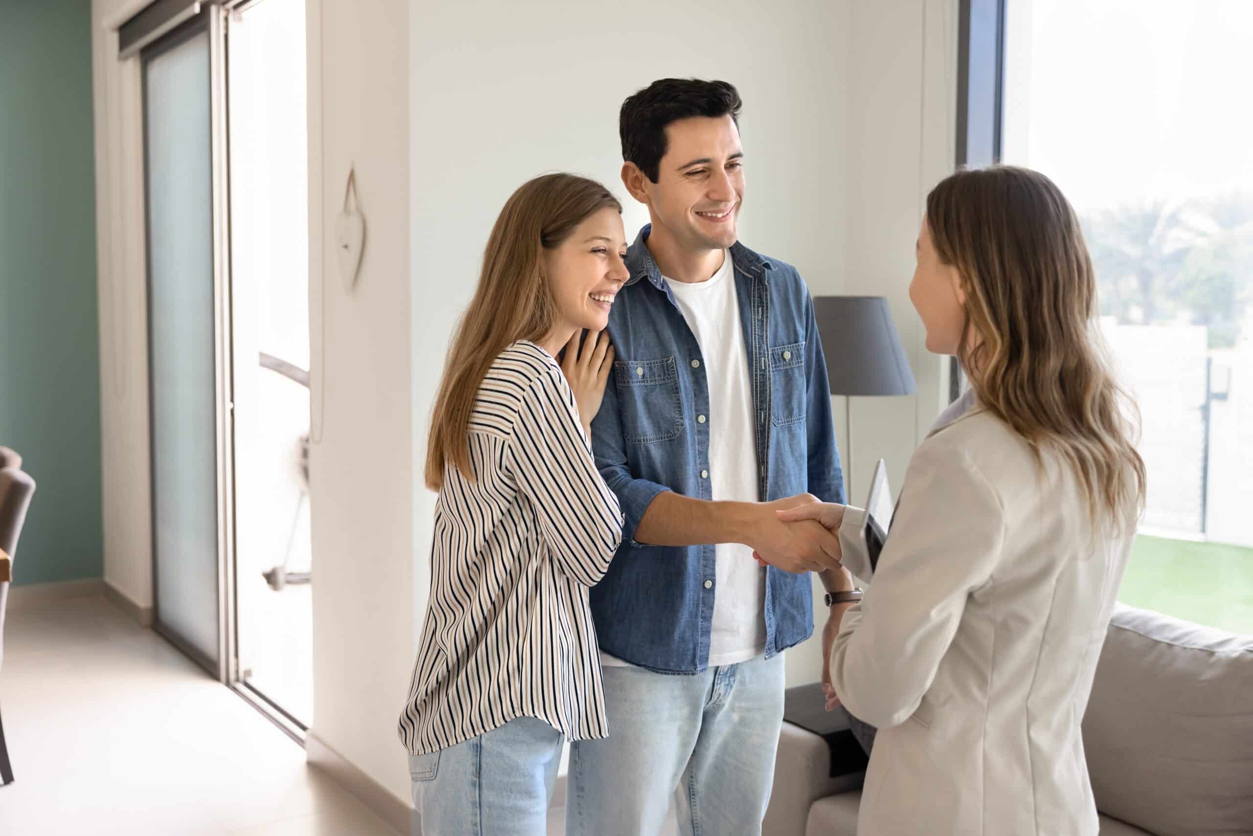 Letting agent shaking hands with a young couple in an empty flat