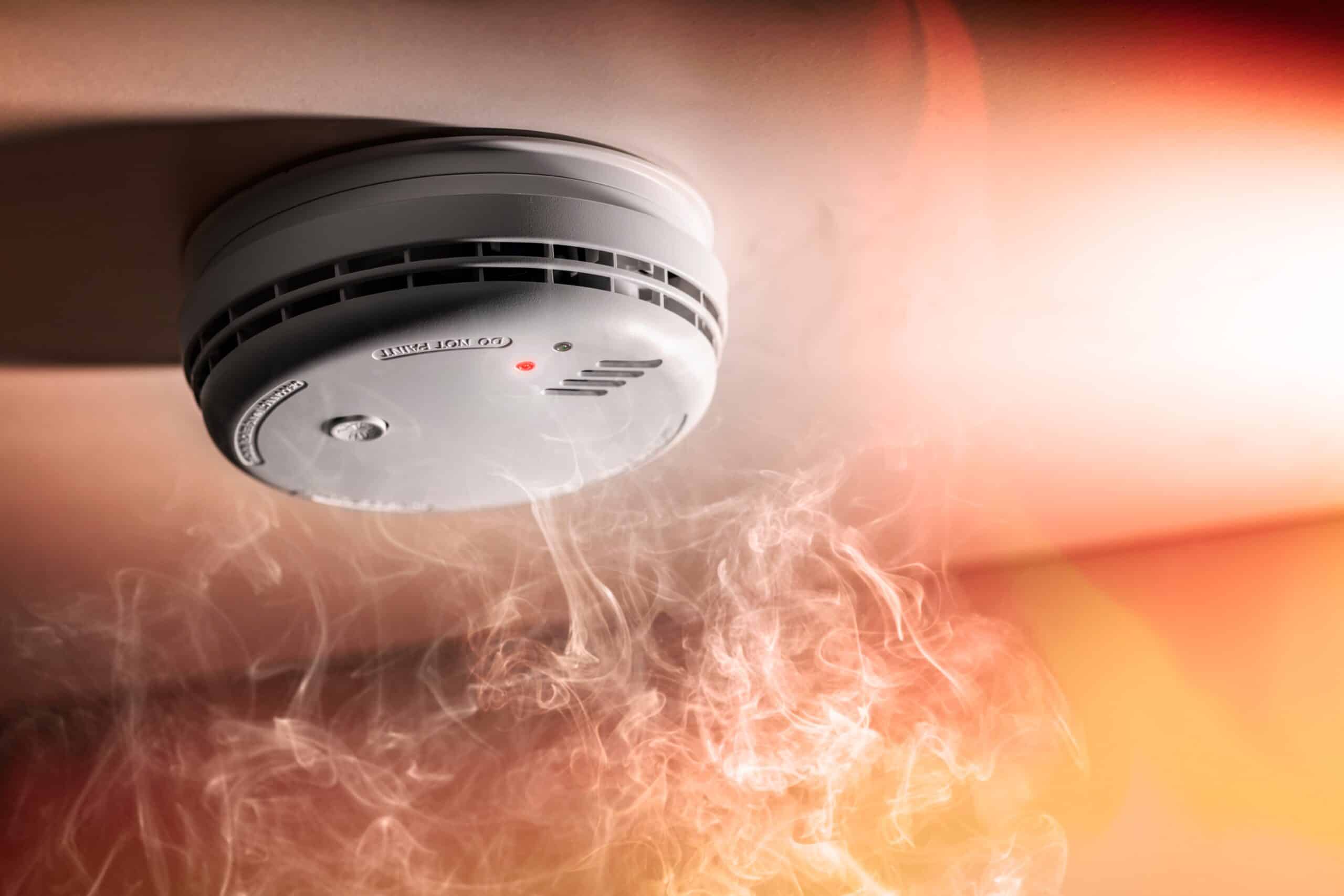 Ceiling smoke alarm with smoke drifting around it