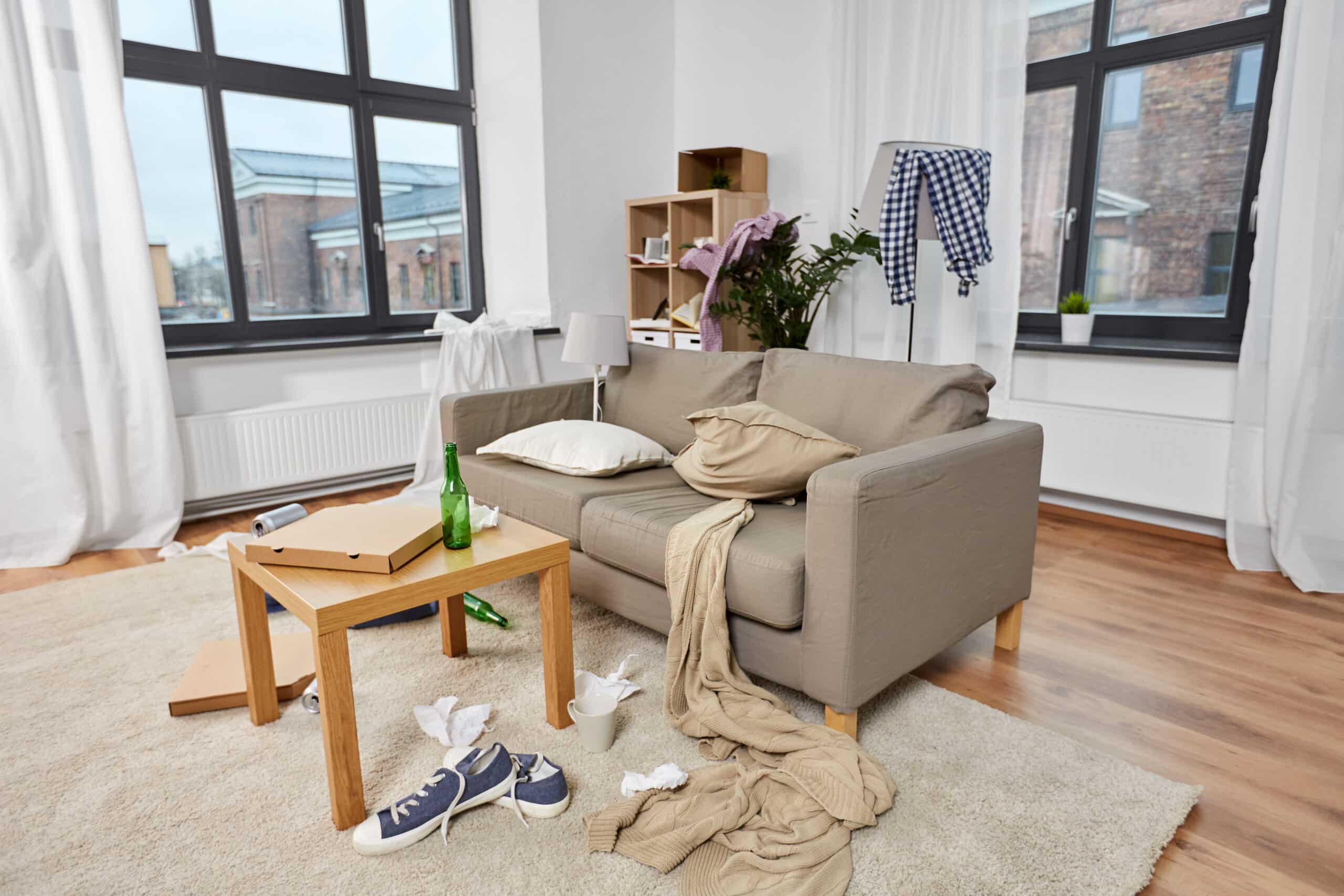 Untidy living room with rubbish and clothes strewn across the floor