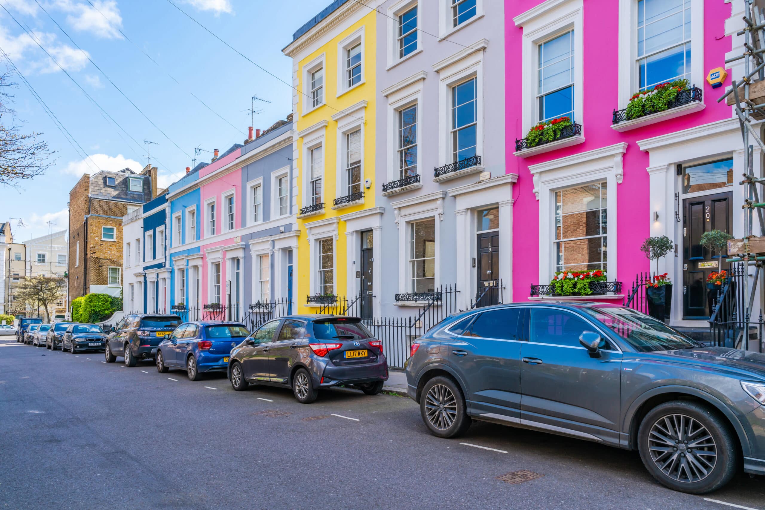 Row of brightly painted terraced townhouses with parked cars