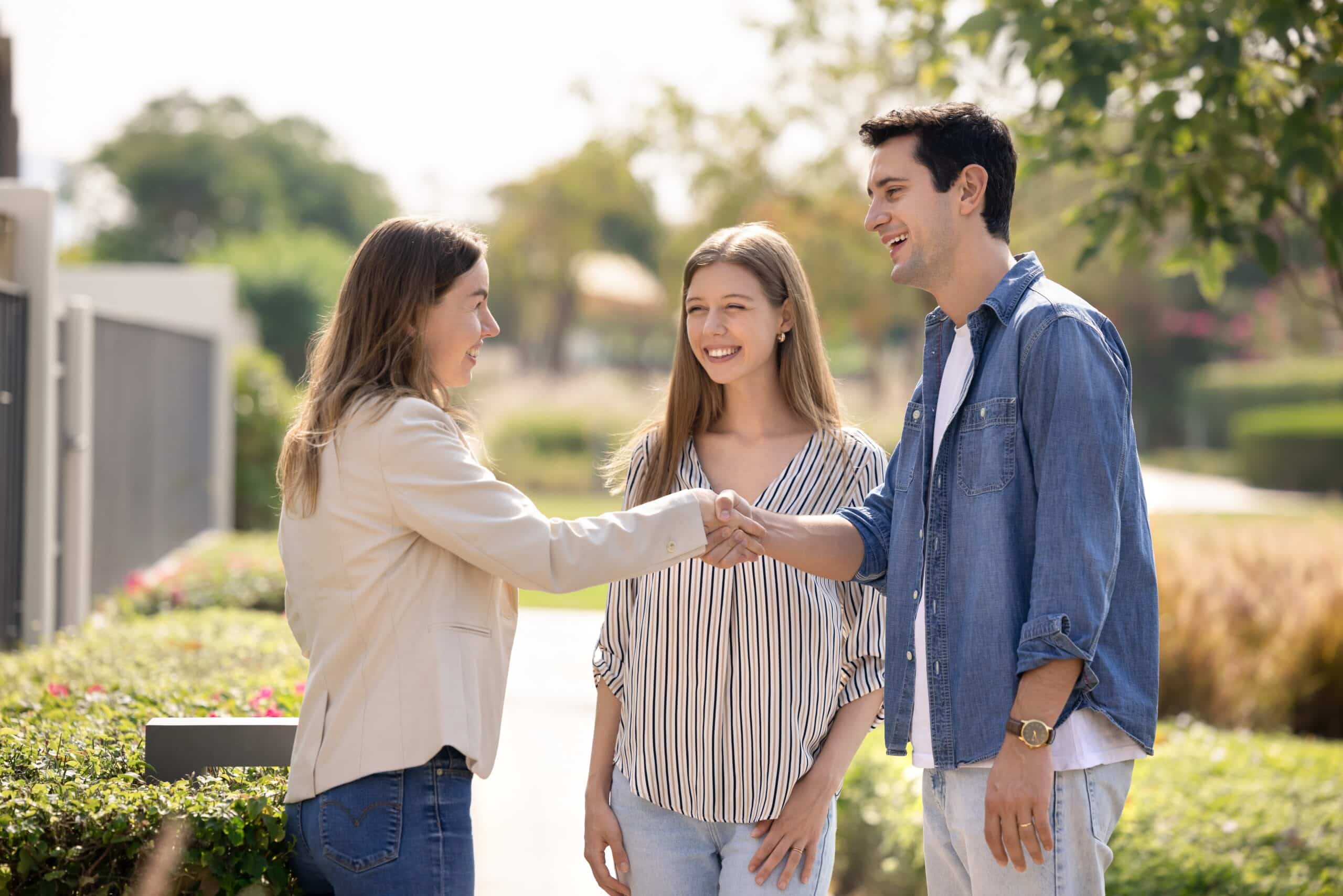 Two women and a man shaking hands in a garden