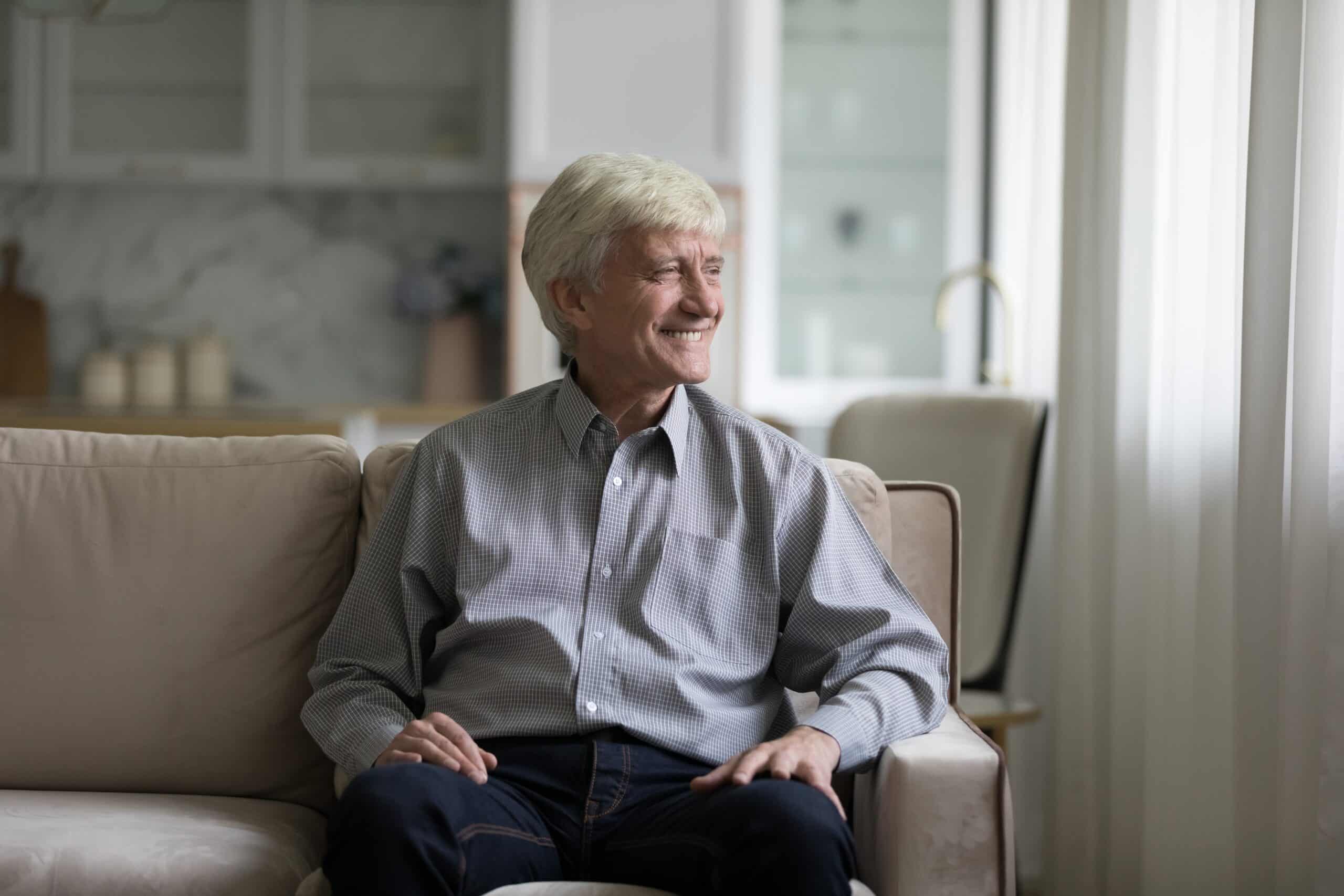 Older man sitting on a sofa beside a window