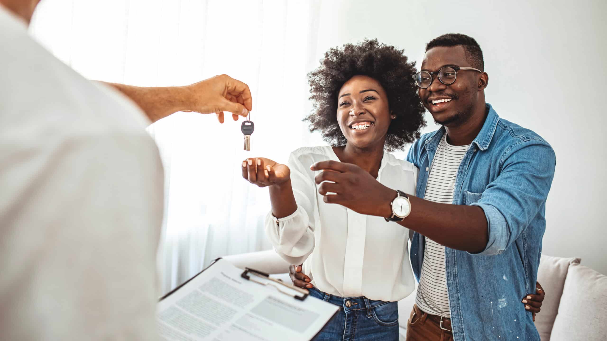 Couple being handed keys while signing a document