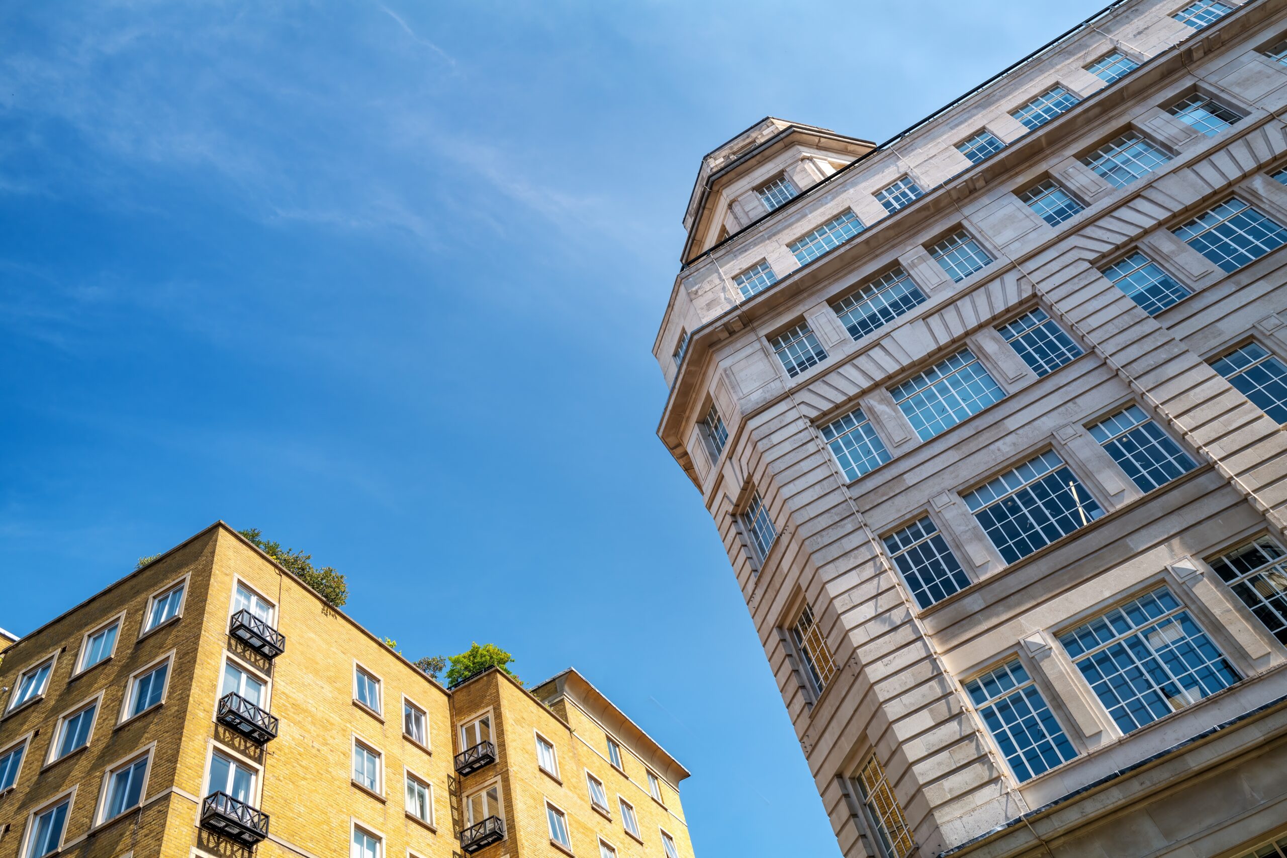 Looking up at tall period apartment buildings against a blue sky
