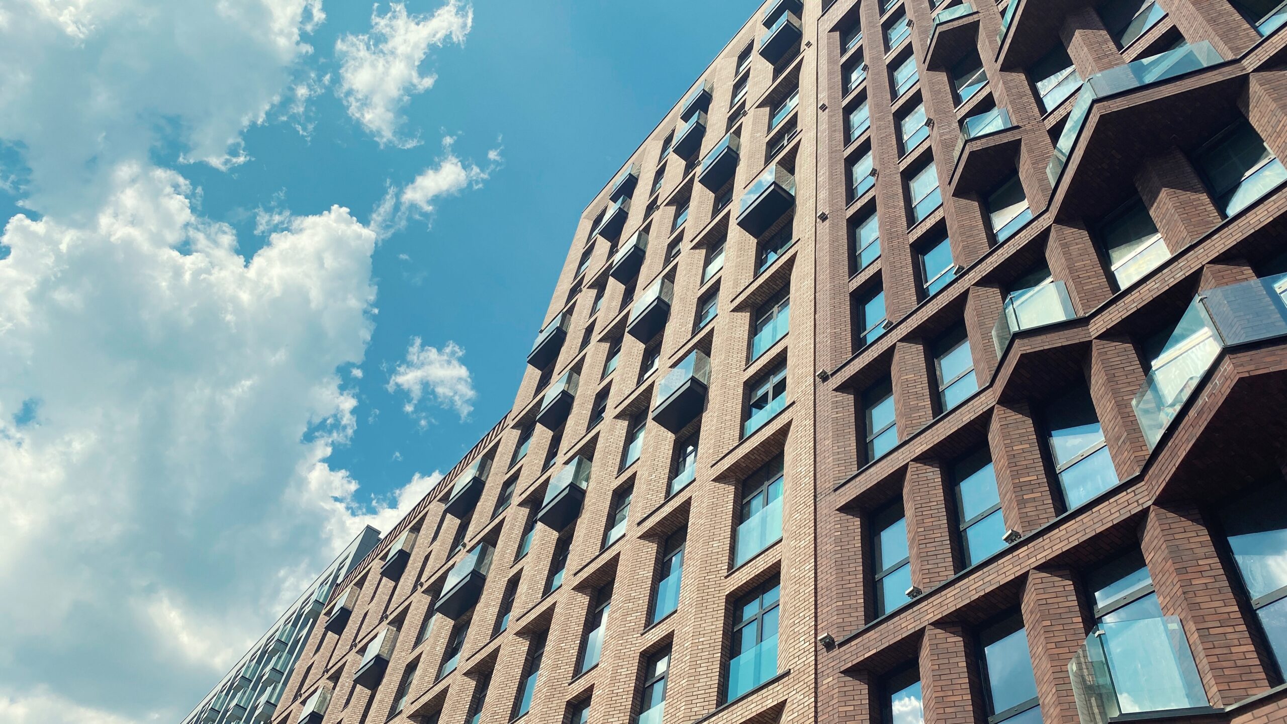 Looking up at a modern brick apartment block against a blue sky