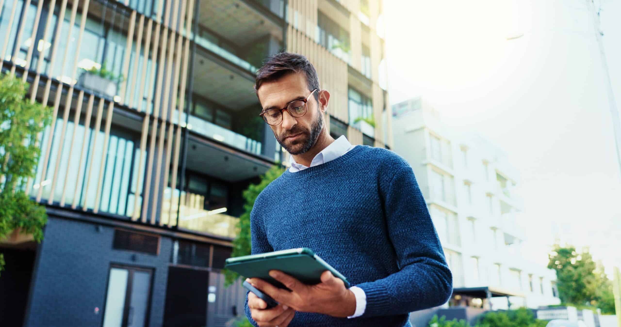 Man with a tablet inspecting a modern apartment building