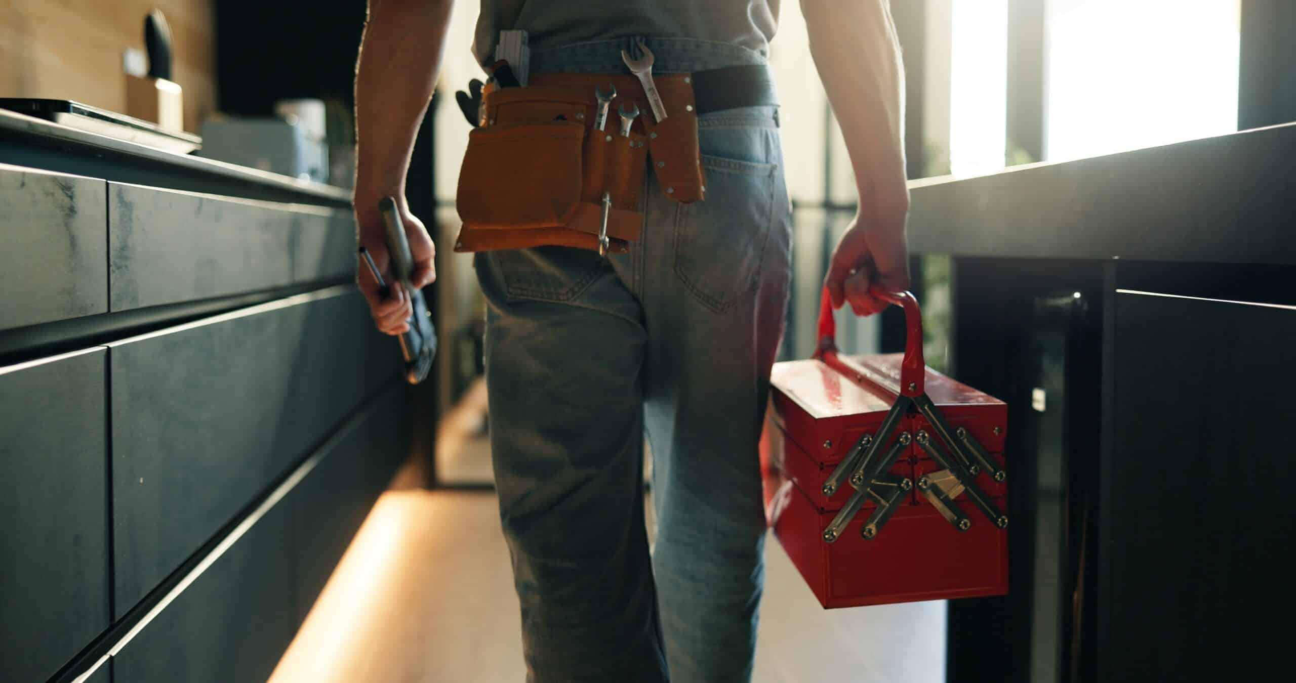 Tradesperson carrying a toolbox and wearing a tool belt